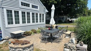 Un patio con una mesa y sillas de piedra, una jardinera de piedra y un paraguas blanco.