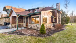 A two-story house with a stone facade, a wooden exterior, and a chimney.