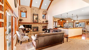 A spacious living room with a fireplace, a stone accent wall, and a large brown sofa.