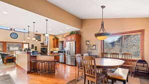 A spacious kitchen with wooden cabinets, a stainless steel refrigerator, and a dining area with a round table and chairs.