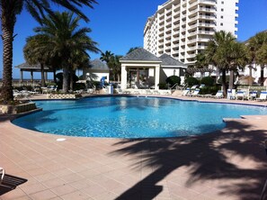 Relax by the resort pool surrounded by palm trees and lounge chairs.