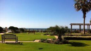 A well-maintained grassy area with a wooden bench, a pergola, and a view of the sea. - Beach Club 3bd, 3ba. First floor on the beach. Super Special rate for Aug & Sept (Gulf Shores)