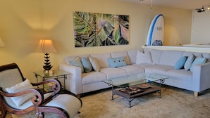 A living room with a sofa, armchair, coffee table, and a surfboard on a stand. - 180 degree Ocean Front Unobstructed View. Sleeps 8
New appliances. (Princeville)