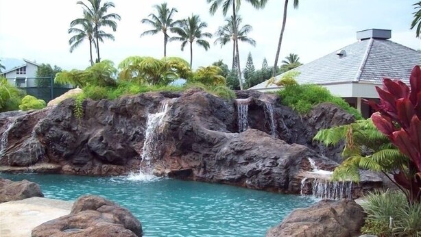 A pool with a waterfall feature surrounded by rocks and palm trees. - 180 degree Ocean Front Unobstructed View. Sleeps 8
New appliances. (Princeville)