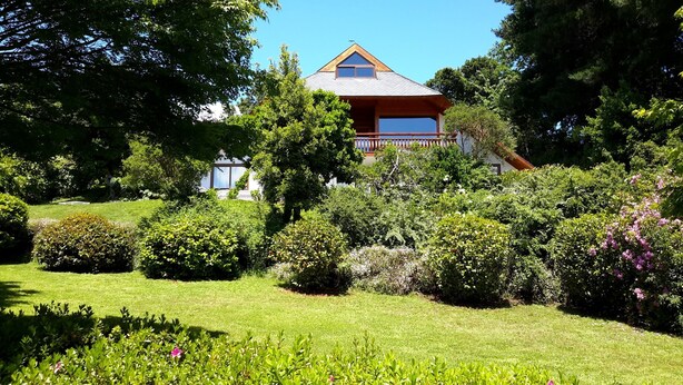 A house surrounded by lush greenery and a well-maintained lawn.