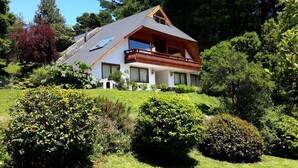 A modern house with a sloped roof, large windows, and a balcony.