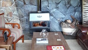 A cozy attic room with a stone wall, a fireplace, a wooden ceiling, and a seating area with a coffee table.