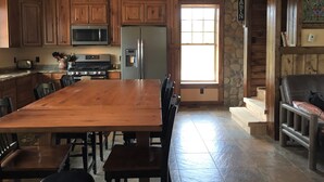 A spacious kitchen with wooden cabinets, a large island, stainless steel appliances, and a stone accent wall. - Secluded Lookout Cabin- Fishing, ATV Trails, Canoe, Kayak & Campfires. (Shevlin)