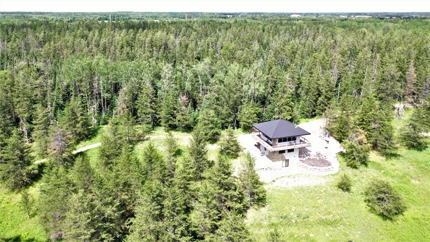 A modern cabin with a dark roof, surrounded by dense forest, featuring a spacious deck and a stone foundation. - Secluded Lookout Cabin- Fishing, ATV Trails, Canoe, Kayak & Campfires. (Shevlin)