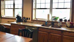 A kitchen with wooden cabinets, a sink, and a window with a view of greenery outside. - Secluded Lookout Cabin- Fishing, ATV Trails, Canoe, Kayak & Campfires. (Shevlin)
