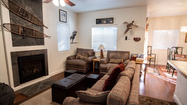 A living room with a fireplace, a sofa set, a dining area, and a ceiling fan. - 4 Br 3.5 baths Towne Home Driggs Idaho. Close to skiing, Jackson Hole, GTNP, YNP (Driggs)