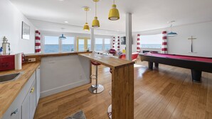 A modern kitchen with a wooden countertop, a red bar stool, and a pool table. - Waterfront Cottage on Lake Erie (Huron)