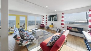 A modern living room with a large window, a sofa, a coffee table, and a TV. - Waterfront Cottage on Lake Erie (Huron)