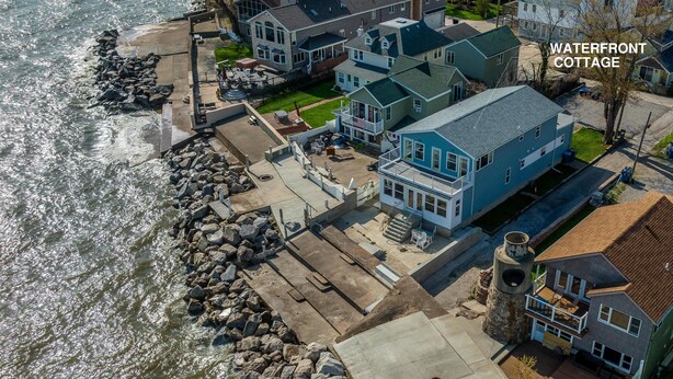 A waterfront cottage with a patio, a view of the water, and a stone wall. - Waterfront Cottage on Lake Erie (Huron)
