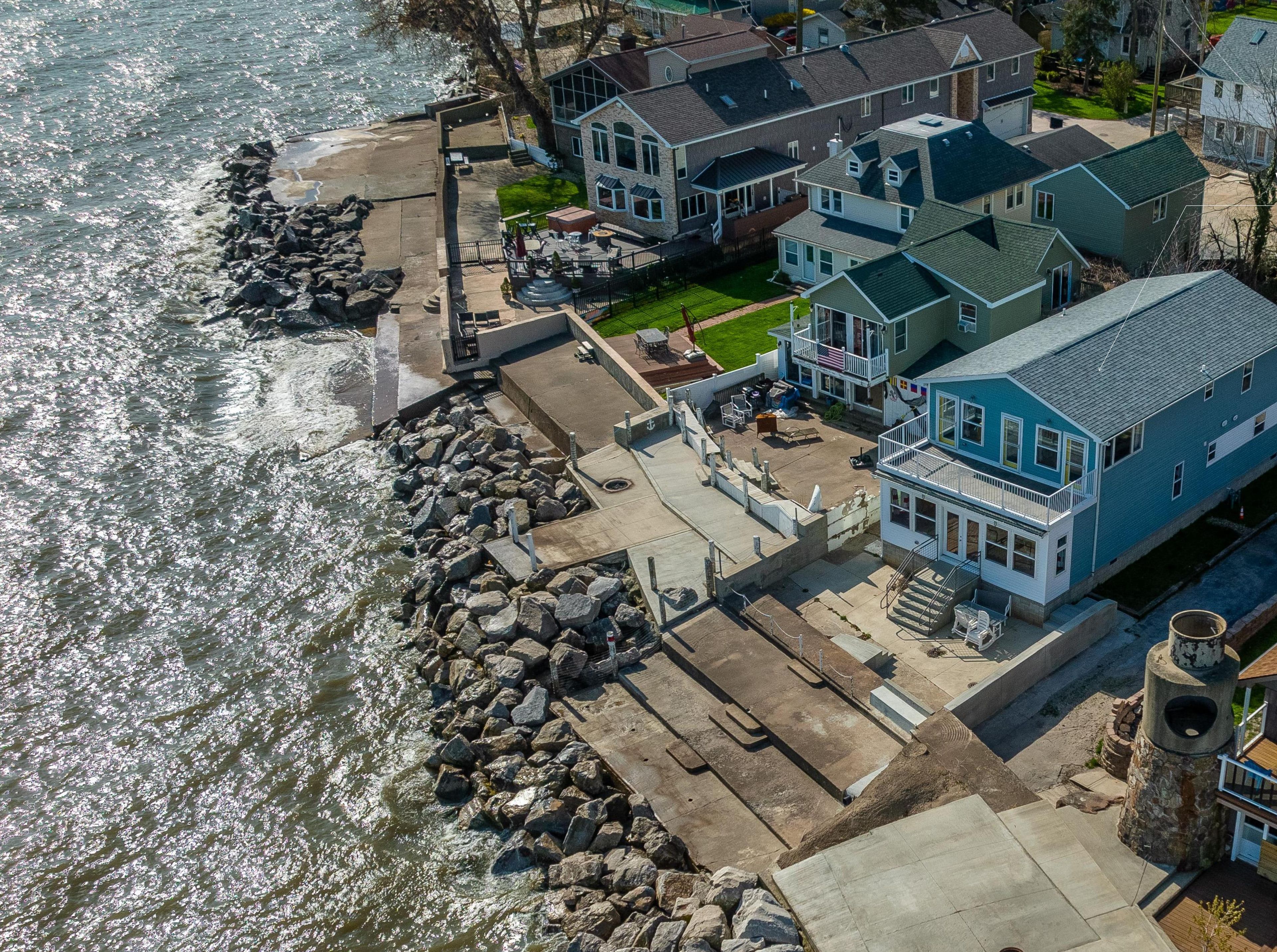 A waterfront cottage with a patio, a view of the water, and a stone wall.