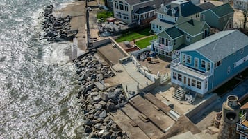 A waterfront cottage with a patio, a view of the water, and a stone wall.