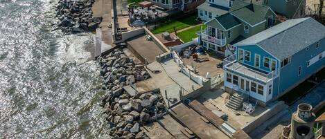 A waterfront cottage with a patio, a view of the water, and a stone wall.