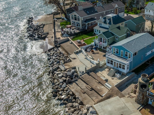 A waterfront cottage with a patio, a view of the water, and a stone wall. - Waterfront Cottage on Lake Erie (Huron)