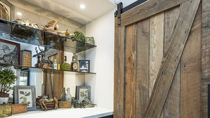 A kitchen with dark cabinets, a wooden barn-style door, and shelves with various items.