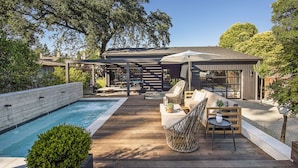 A wooden deck with a pool, outdoor furniture, and a covered seating area.