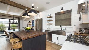 A modern kitchen with a central island, stainless steel appliances, and pendant lighting.