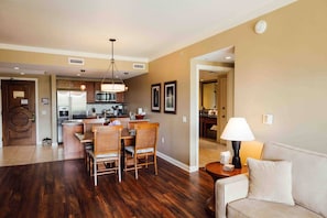 A spacious living area with a dining table and chairs, a sofa, a lamp, and a kitchen in the background. - KLVR presents Honua Kai K612*Two bedrooms*one bath (Lahaina)