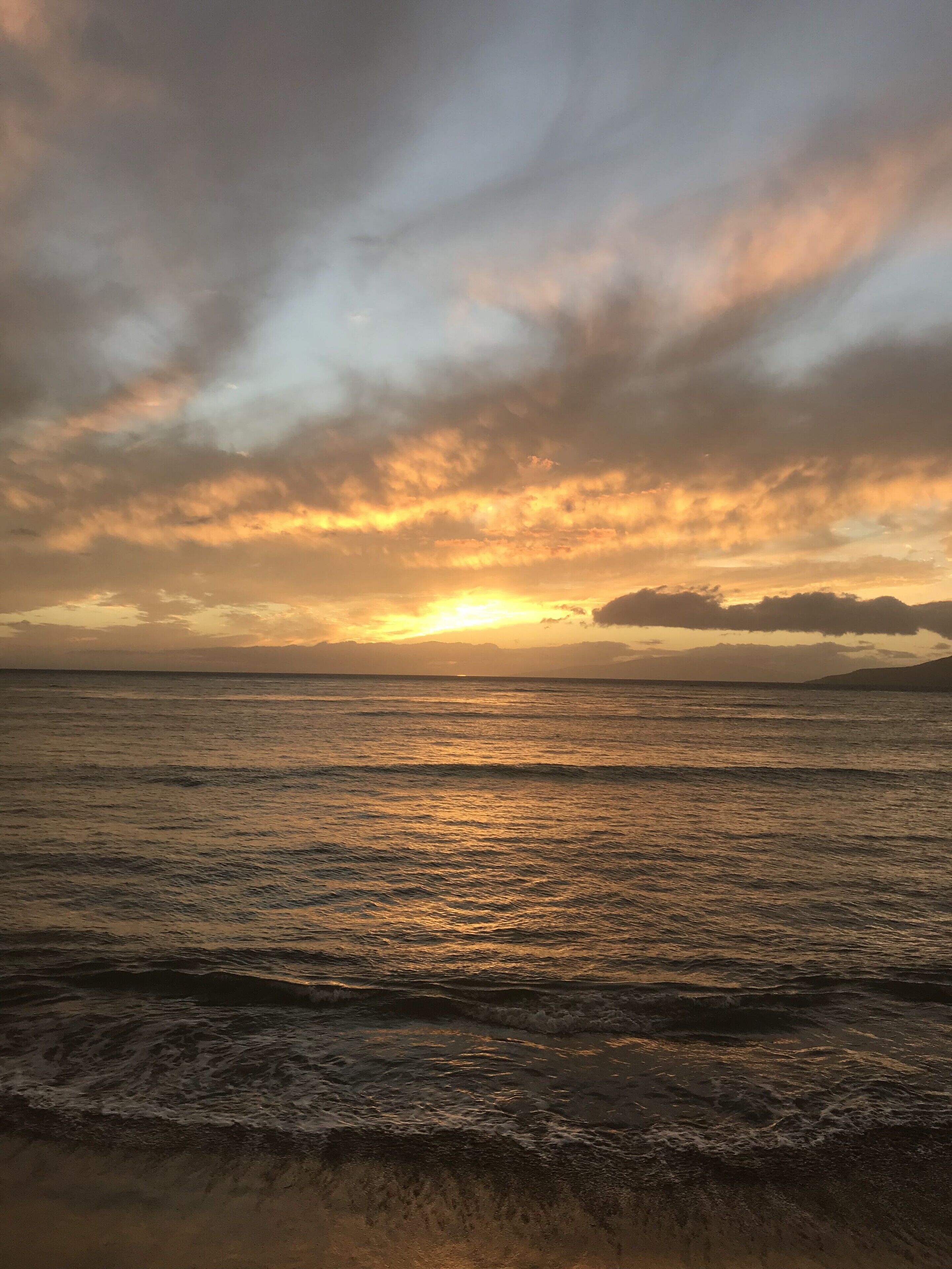Ein Strand mit Wellen und einem Sonnenuntergang.