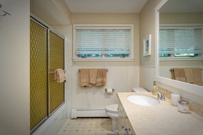 Une salle de bain équipée d’une douche, de toilettes, d’un lavabo et d’une fenêtre avec des stores.