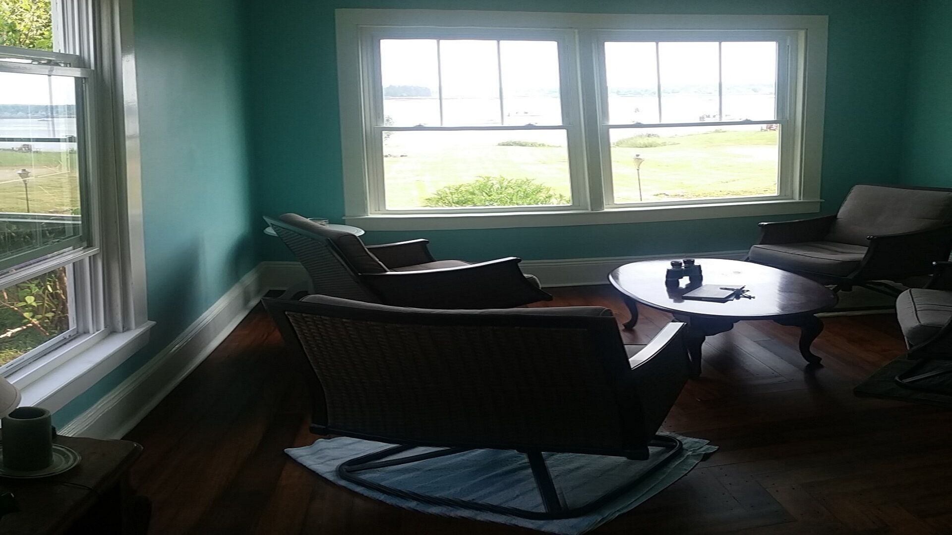 A room with teal walls, a large window, and a round table with chairs.