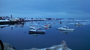 Un port où sont amarrés plusieurs bateaux, un paysage enneigé et un ciel calme au crépuscule.