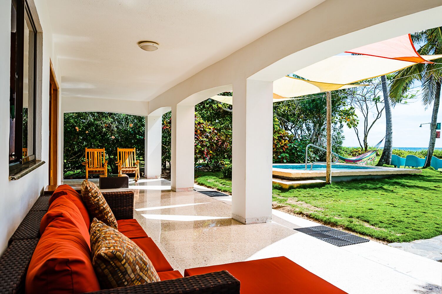 Un espacio lounge moderno al aire libre con piscina, mobiliario y vista al océano.
