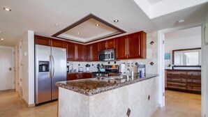 A modern kitchen with a central island, stainless steel appliances, and wooden cabinetry. - 50' of Ocean Front * Exclusive Ground Level Patio * AC (San Diego)