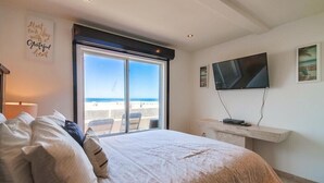 A bedroom with a large bed, a TV mounted on the wall, and a window overlooking the beach. - 50' of Ocean Front * Exclusive Ground Level Patio * AC (San Diego)