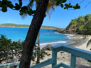 A beach with clear blue water, a sandy shore, and a view of the sea.