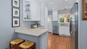 A modern kitchen with white cabinetry, a central island, and a stainless steel refrigerator. - Private Hot Tub/Short Walk to Downtown (Napa)
