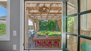 A room with a wooden table and red chairs, a window with a view of a garden, and a ceiling fan. - Private Hot Tub/Short Walk to Downtown (Napa)