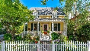 A yellow house with a white picket fence, a front porch, and a chimney. - Private Hot Tub/Short Walk to Downtown (Napa)