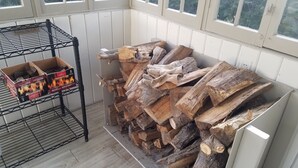 A room with a metal rack holding firewood and a box of StarterLogg fire starters. - Beautiful Lake Front Home On Como with boat and motor included (Lake Geneva)