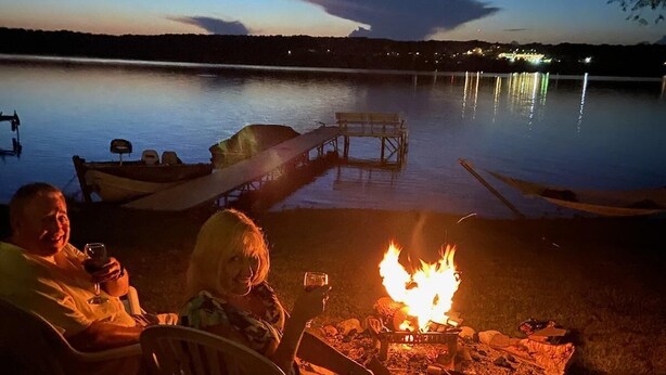 A lakeside evening with a campfire, chairs, and a table with drinks. - Beautiful Lake Front Home On Como with boat and motor included (Lake Geneva)