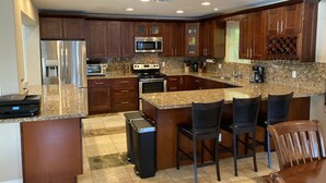 A modern kitchen with granite countertops, stainless steel appliances, and dark wood cabinetry.