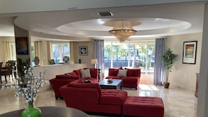 A spacious living room with a large red sectional sofa, a green vase on a table, and a chandelier.
