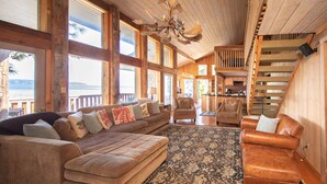 A spacious living area with a large sofa, a smaller sofa, and a leather armchair, all arranged around a patterned rug.