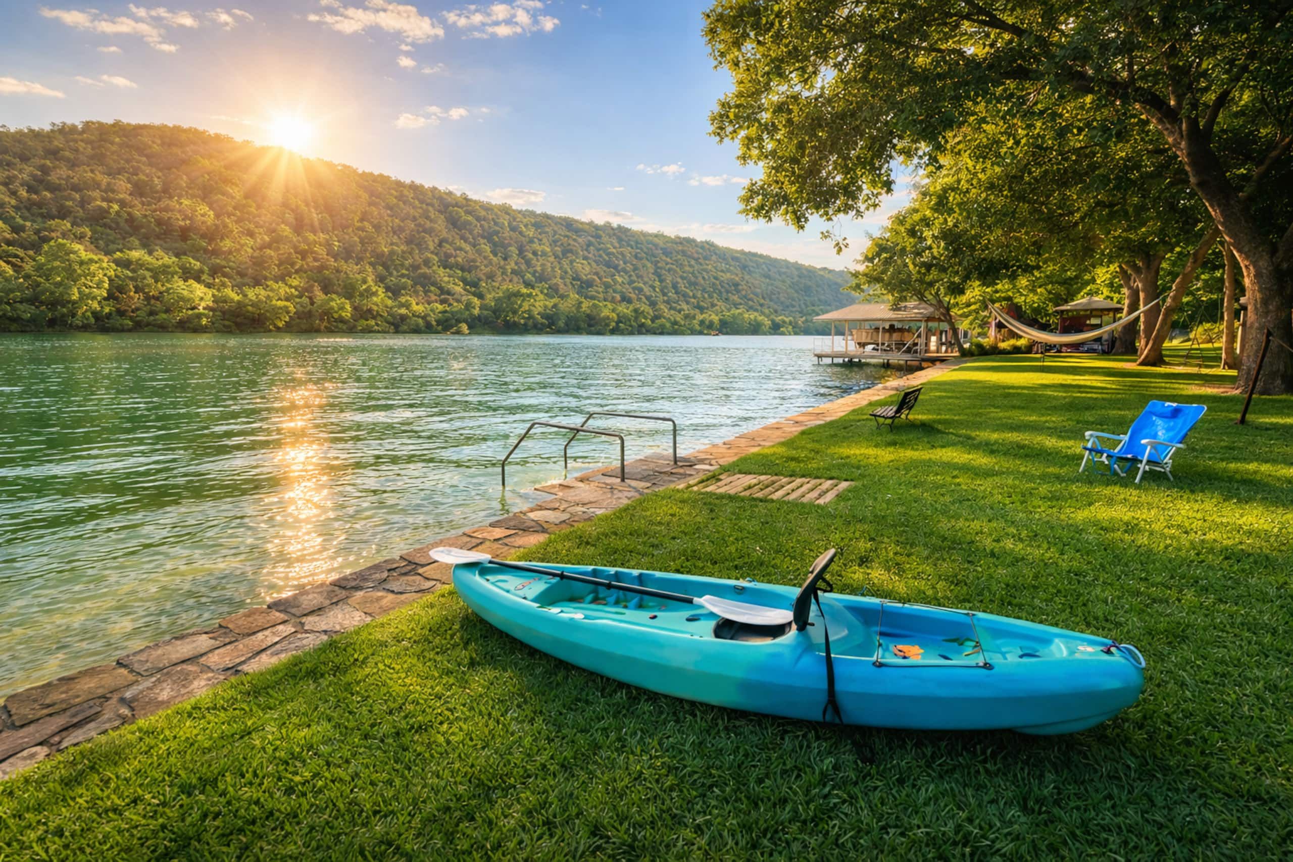 Un paisaje junto al lago con un kayak, un muelle y una zona verde con una silla.