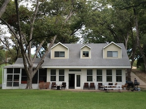 A two-story house with a porch, large windows, and a covered outdoor seating area.