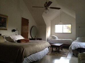 A bedroom with two beds, a ceiling fan, a window, and a mirror.