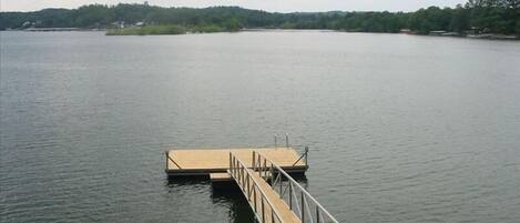 A wooden dock extending into calm water with a forested shoreline in the background.