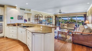 A kitchen with white cabinets, granite countertops, and a built-in oven. - WOW- New 2bd/2ba, Largest Lanai w/Ocean & Golf Course Views, Lowest Resort Fee! (Lahaina)