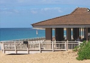 A beachside building with a sloped roof, a white railing, and a view of the ocean.