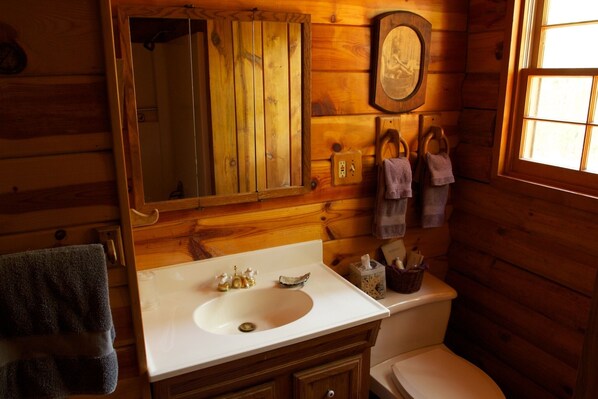 Un baño rústico con tocador, lavamanos e inodoro de madera.