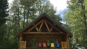 A wooden cabin with a porch and colorful Adirondack chairs. - Loons Nest - Cozy, secluded 4 bedroom log cabin in the heart of the wilderness! (Tyaughton Lake)